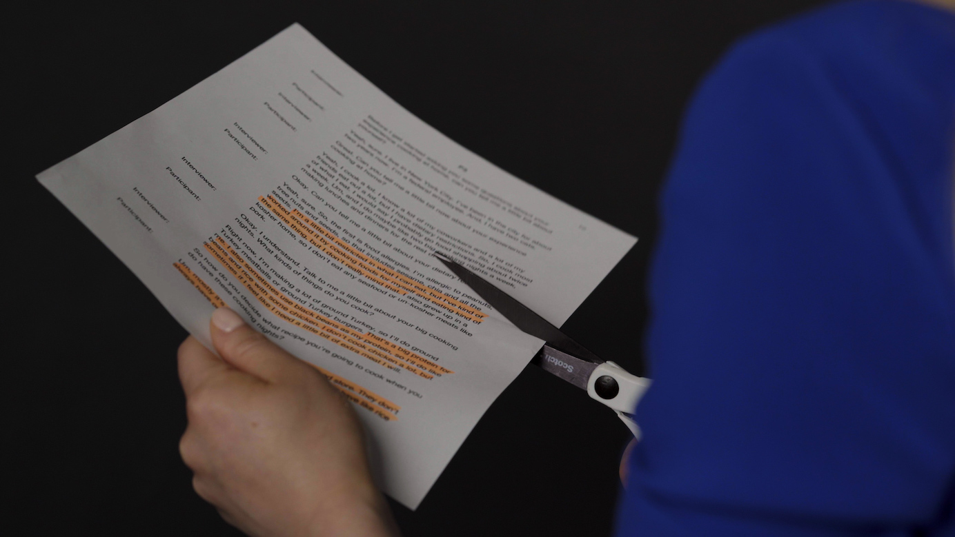 A photograph of a highlighted transcript being cut up into sections.