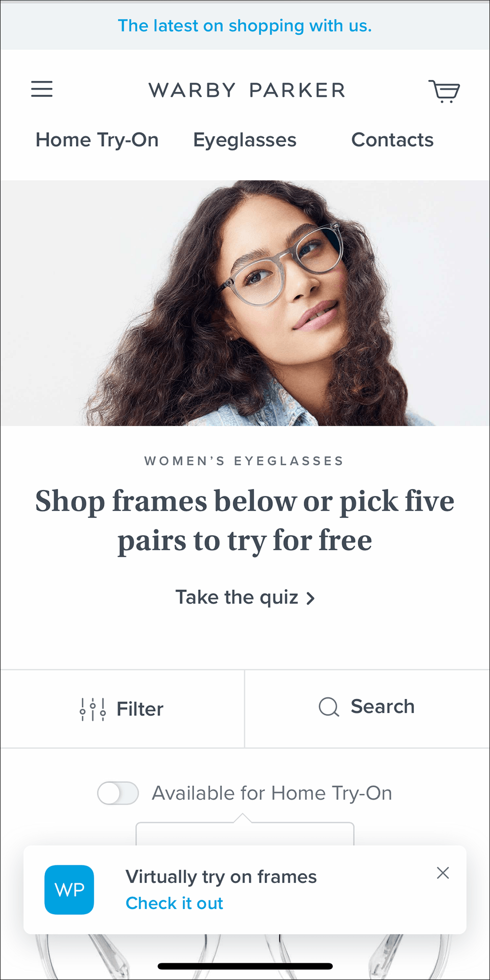 Screenshot of Warby Parker mobile website homepage, showing a white banner element at the bottom of the screen stating "Virtually try on frames" and "Check it out"