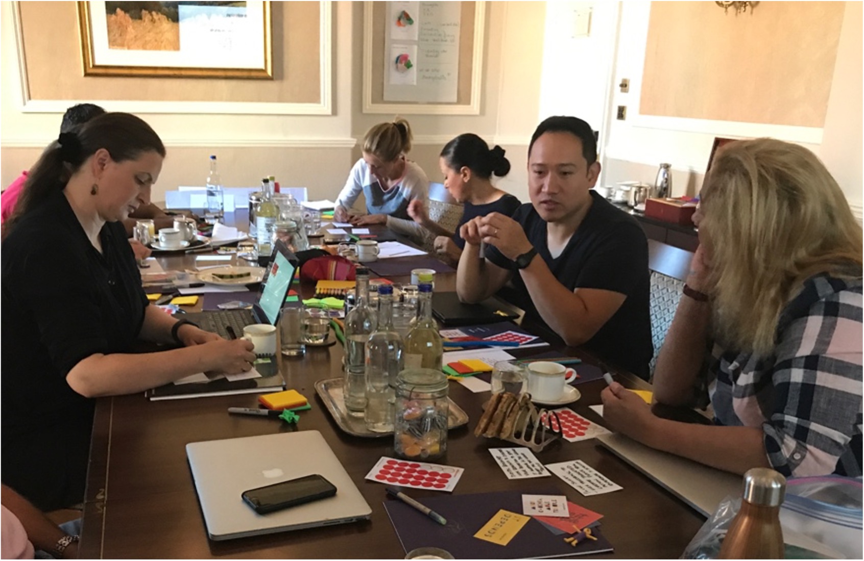 A UX team seated around a conference table, brainstorming stories of value on index cards