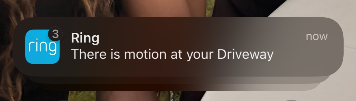 Screenshot of a Ring camera notification reading 'There is motion at your Driveway' with a badge indicating 3 notifications.
