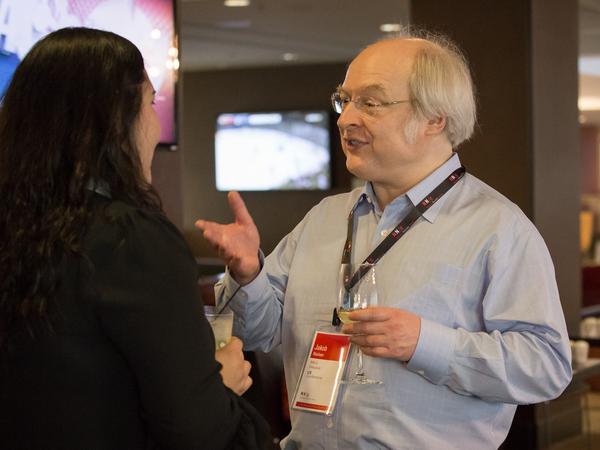 Jakob Nielsen speaking with conference attendees at a happy hour